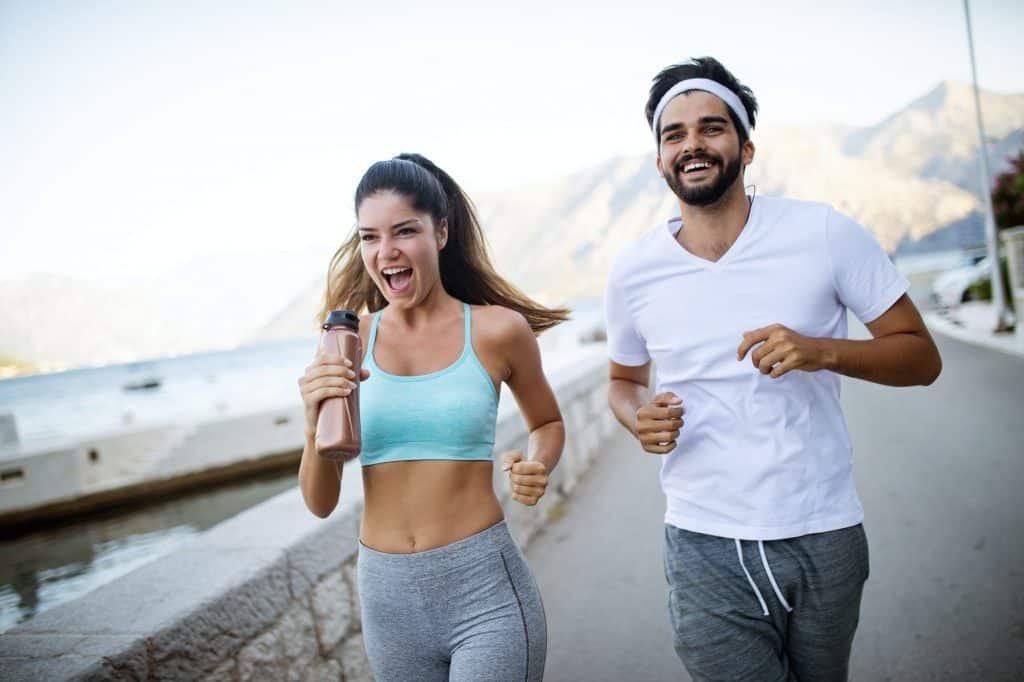 Happy young fit people couple running outdoor