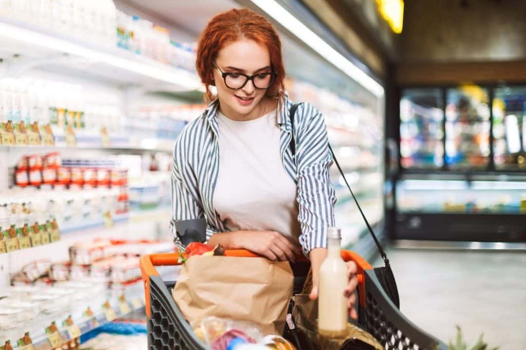 Pretty girl in eyeglasses and striped shirt with shopping cart f